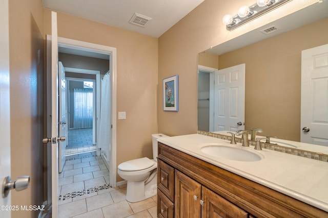 bathroom featuring vanity, tile patterned flooring, and toilet