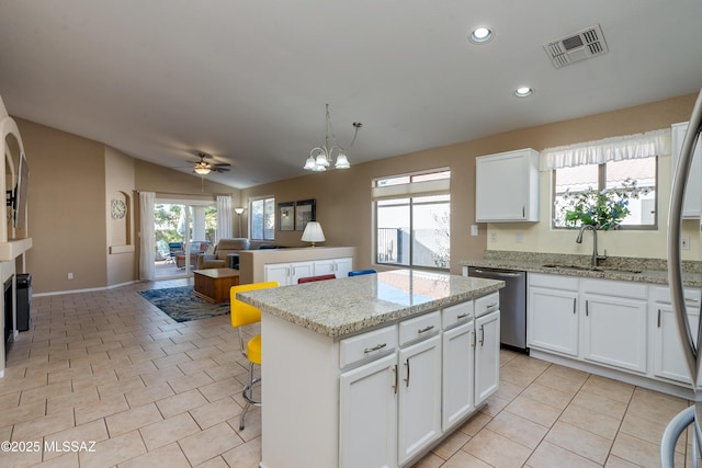 kitchen featuring stainless steel appliances, a center island, white cabinets, and light stone counters