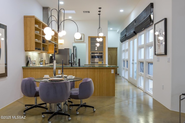 kitchen with sink, hanging light fixtures, backsplash, stainless steel appliances, and kitchen peninsula