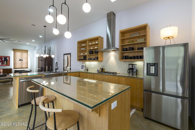 kitchen with wall chimney exhaust hood, a kitchen bar, kitchen peninsula, pendant lighting, and stainless steel appliances