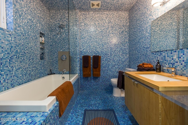 bathroom with tile walls, vanity, a bathing tub, and toilet