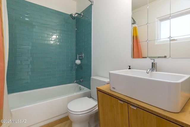 full bathroom featuring tiled shower / bath, vanity, and toilet