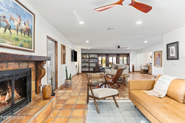 living room with a tiled fireplace and ceiling fan