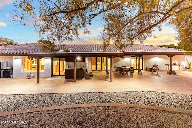 back house at dusk featuring a patio area