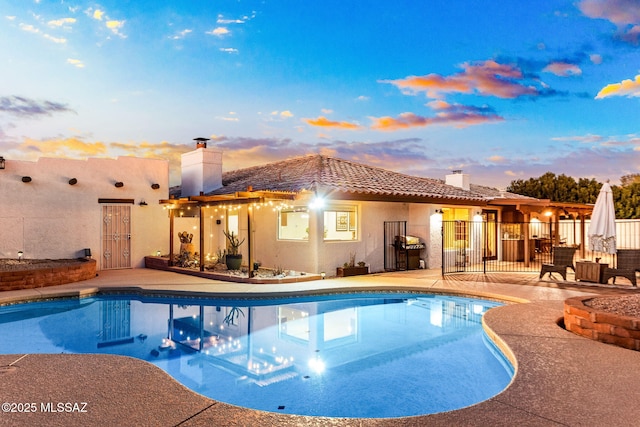 pool at dusk featuring grilling area and a patio area