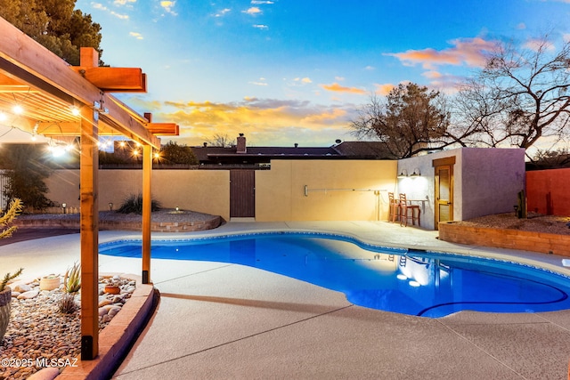 pool at dusk with a patio area