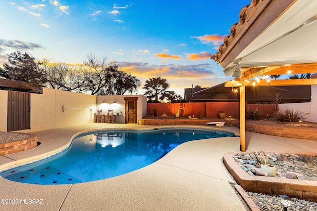 pool at dusk with a diving board and a patio