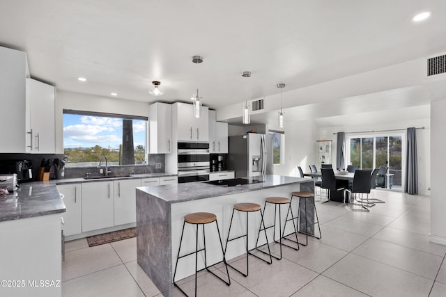 1061 W Roller Coaster Rd, Tucson, AZ 85704 - kitchen featuring a kitchen island, a sink, appliances with stainless steel finishes, a kitchen bar, and backsplash