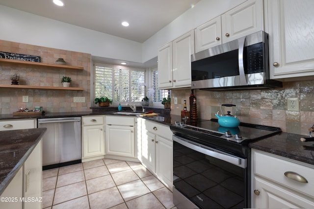 kitchen with stainless steel appliances, light tile patterned flooring, white cabinetry, and decorative backsplash