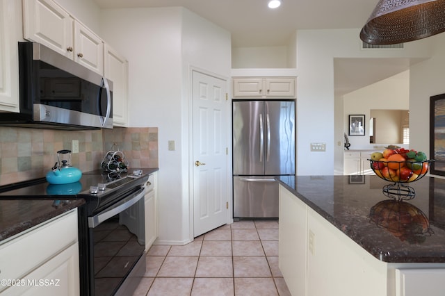 kitchen featuring light tile patterned floors, stainless steel appliances, tasteful backsplash, white cabinets, and dark stone countertops