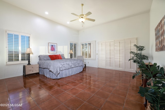 bedroom featuring dark tile patterned floors, multiple windows, a high ceiling, and ceiling fan