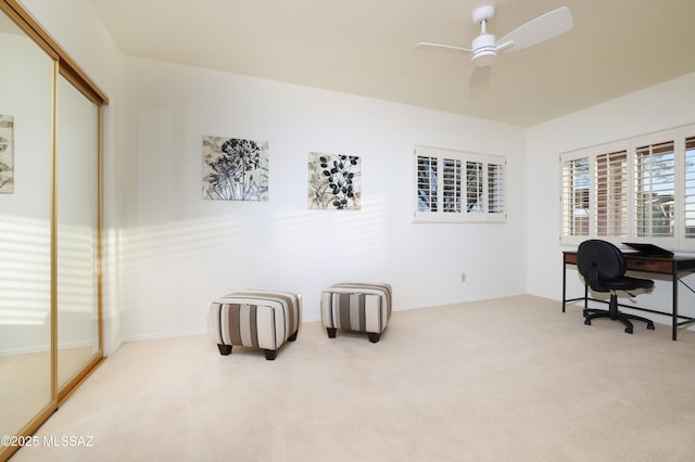 carpeted office space featuring ceiling fan and baseboards