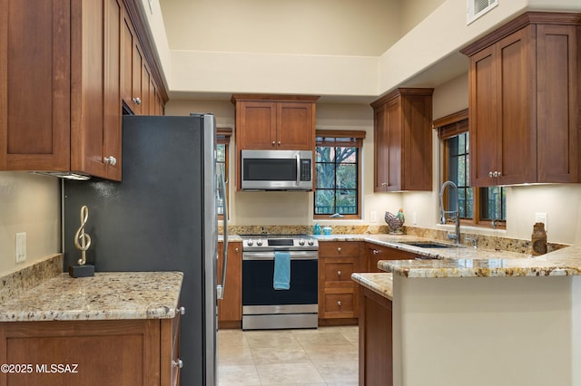 kitchen with light stone counters, sink, kitchen peninsula, and appliances with stainless steel finishes