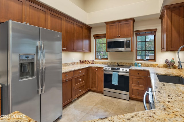 kitchen featuring light tile patterned flooring, stainless steel appliances, light stone countertops, and sink