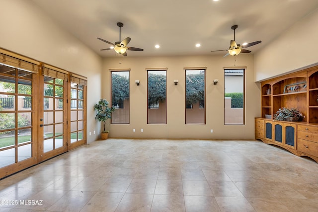 unfurnished living room with light tile patterned floors, a wealth of natural light, french doors, and ceiling fan