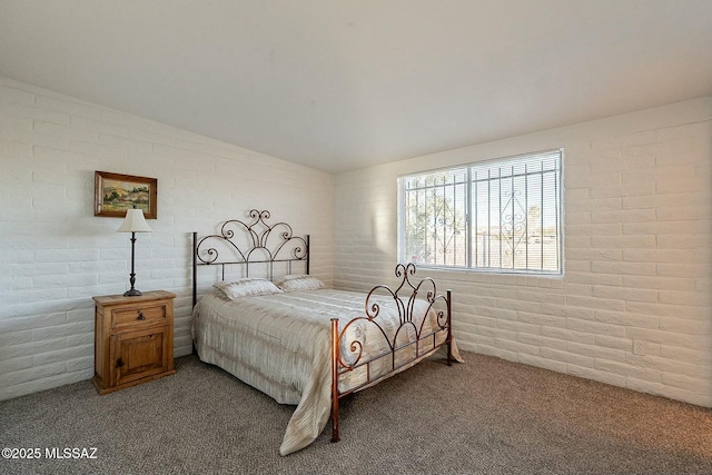 carpeted bedroom with vaulted ceiling and brick wall