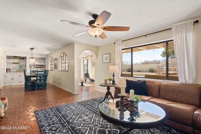 living room with dark tile patterned floors, built in features, and ceiling fan