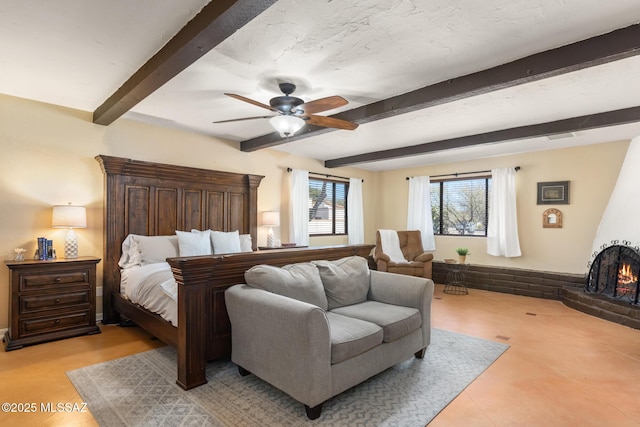 bedroom featuring beamed ceiling, ceiling fan, and a fireplace