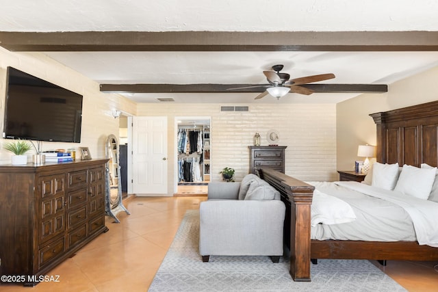 bedroom with light tile patterned floors, ceiling fan, a walk in closet, a closet, and beamed ceiling