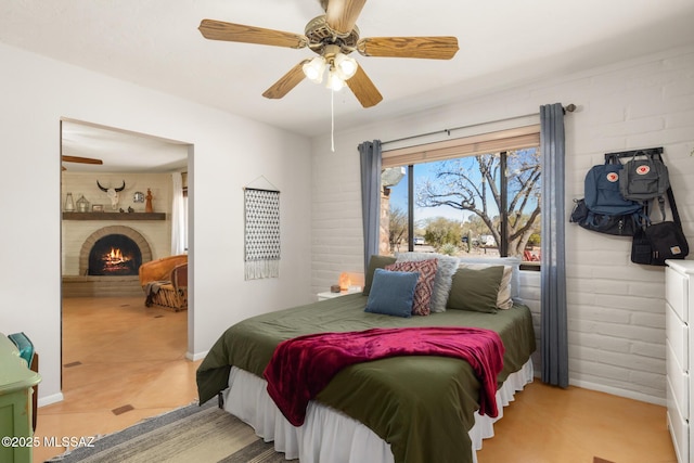 bedroom with ceiling fan, brick wall, and a fireplace