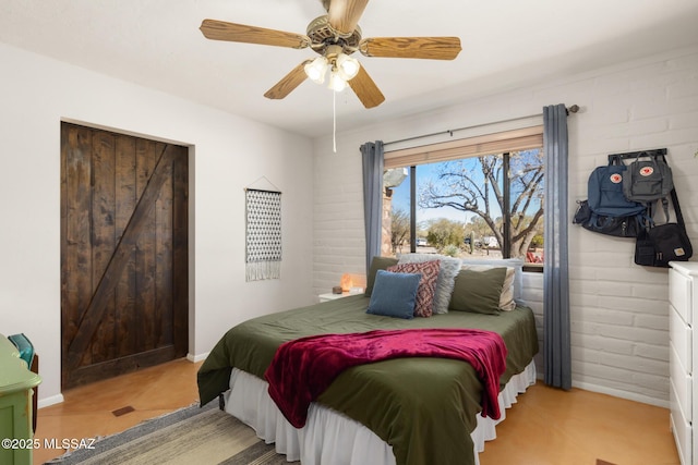 bedroom featuring ceiling fan and brick wall