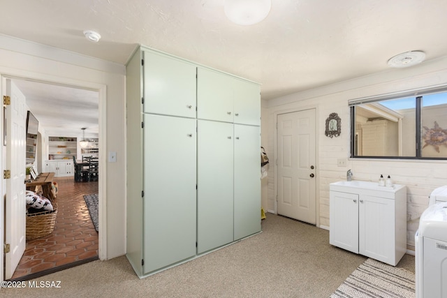 clothes washing area with cabinets, light colored carpet, and washing machine and clothes dryer