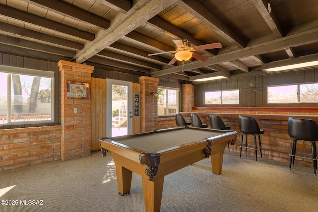 rec room featuring light carpet, bar, beamed ceiling, and brick wall