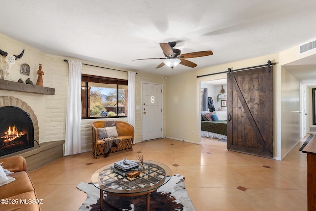 living room featuring light tile patterned floors, a barn door, a brick fireplace, and ceiling fan