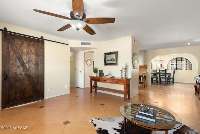 living room featuring a barn door, light tile patterned floors, and ceiling fan