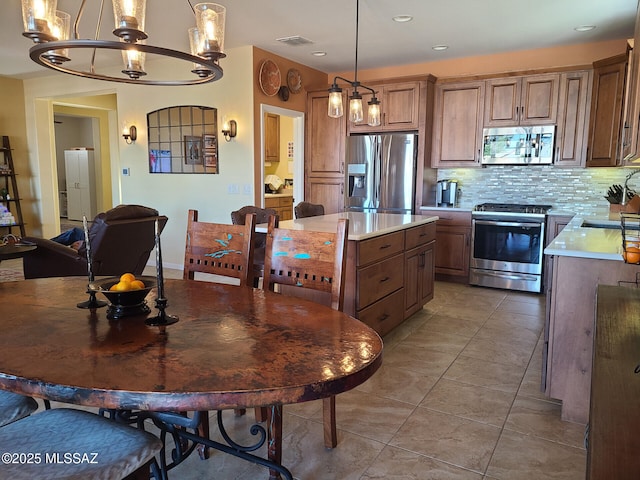 kitchen featuring hanging light fixtures, light tile patterned floors, appliances with stainless steel finishes, a notable chandelier, and decorative backsplash