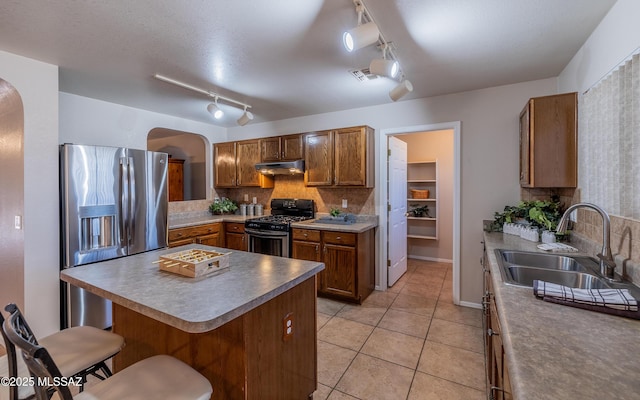 8497 E Hodgman Pl, Tucson, AZ 85747 - kitchen featuring gas range oven, arched walkways, a sink, stainless steel fridge with ice dispenser, and under cabinet range hood