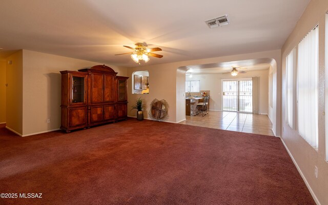 8497 E Hodgman Pl, Tucson, AZ 85747 - living area with ceiling fan, arched walkways, light carpet, and baseboards