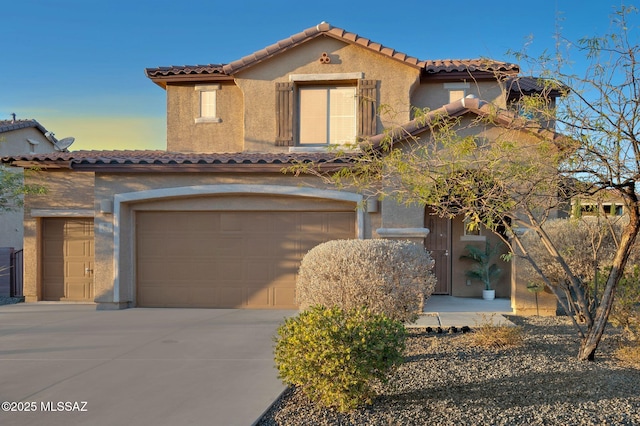 mediterranean / spanish-style house featuring driveway, a tiled roof, a garage, and stucco siding