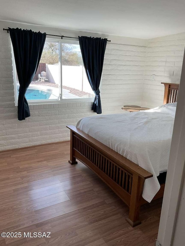 bedroom with hardwood / wood-style floors, access to exterior, and brick wall