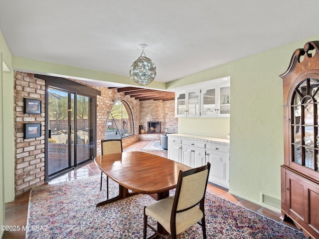 dining area featuring light tile patterned floors, a textured wall, and a fireplace