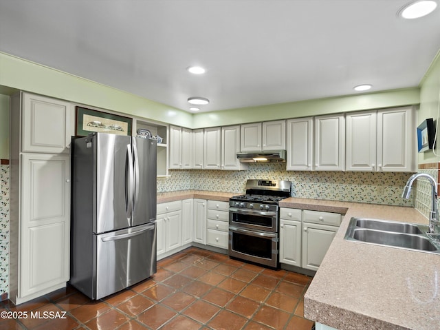 kitchen featuring under cabinet range hood, a sink, light countertops, appliances with stainless steel finishes, and tasteful backsplash