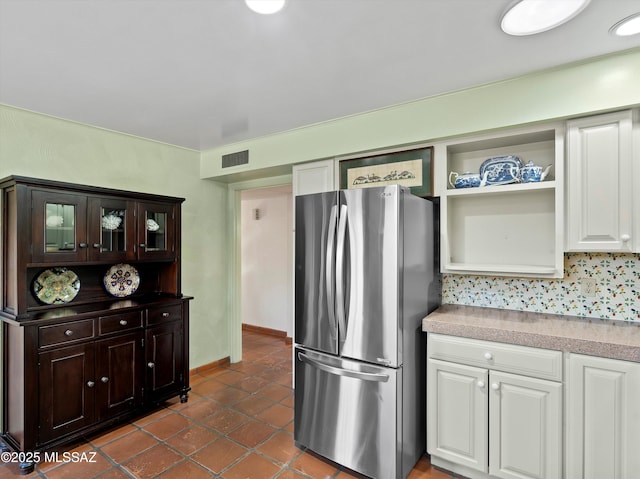 kitchen with visible vents, light countertops, freestanding refrigerator, and white cabinets