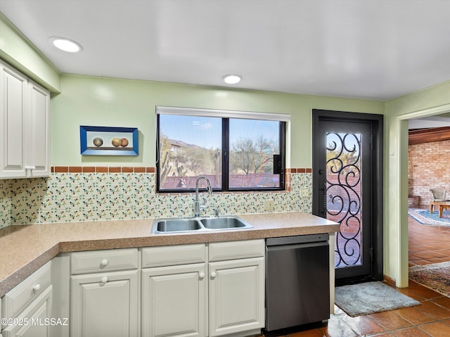 kitchen featuring light countertops, white cabinets, a sink, and dishwashing machine