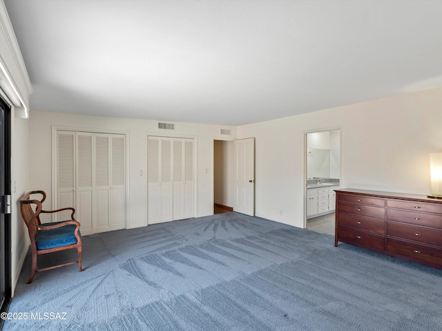 unfurnished bedroom with carpet floors, visible vents, two closets, and ensuite bathroom