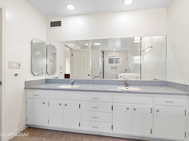 bathroom featuring double vanity, visible vents, a sink, and recessed lighting