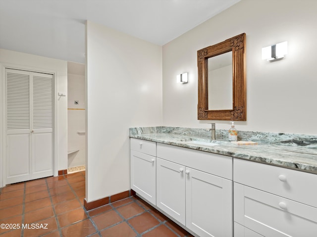 bathroom featuring tile patterned flooring, a closet, vanity, and baseboards