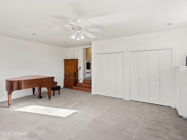 interior space with light carpet, a ceiling fan, washer / clothes dryer, and two closets