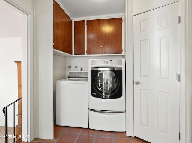 washroom featuring washing machine and dryer, cabinet space, and dark tile patterned floors