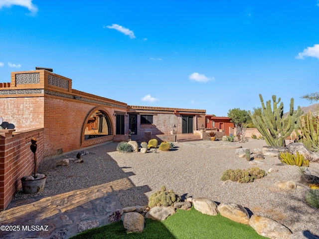 rear view of house featuring brick siding and a patio area