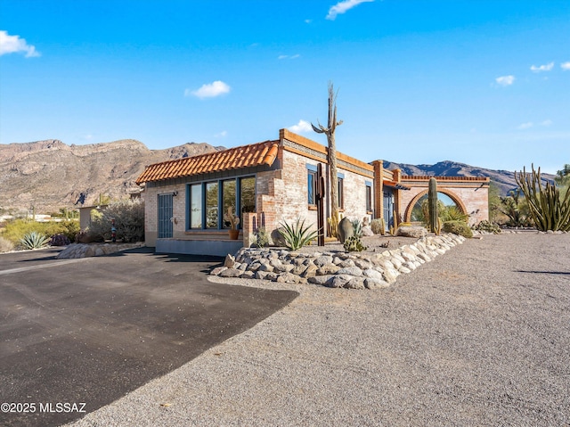 view of front of house with stone siding, a tile roof, and a mountain view