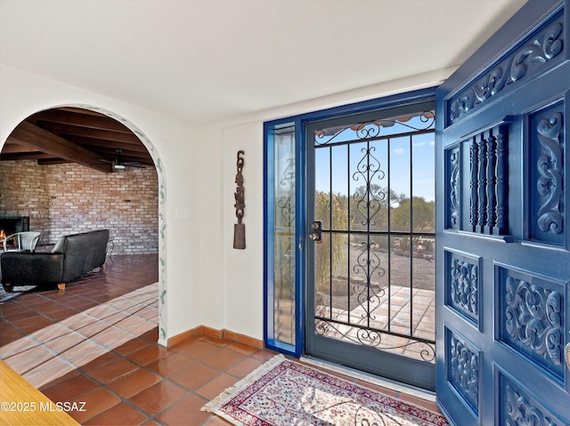 foyer featuring brick wall, dark tile patterned floors, and baseboards