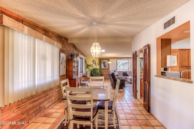 dining space with visible vents, a textured ceiling, brick wall, and light tile patterned flooring