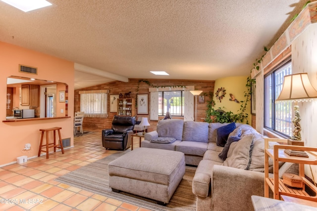 living room with visible vents, vaulted ceiling, a textured ceiling, and light tile patterned flooring