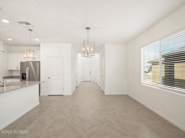 unfurnished dining area featuring visible vents, baseboards, recessed lighting, a notable chandelier, and a sink