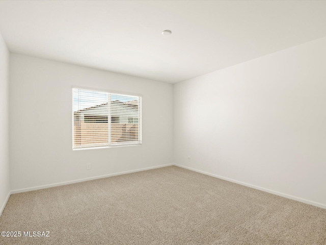 carpeted spare room featuring baseboards